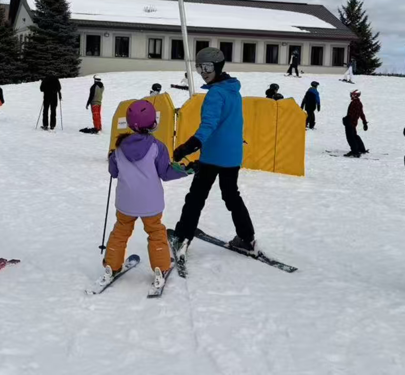 An instructor guiding a young skier on the beginner slope